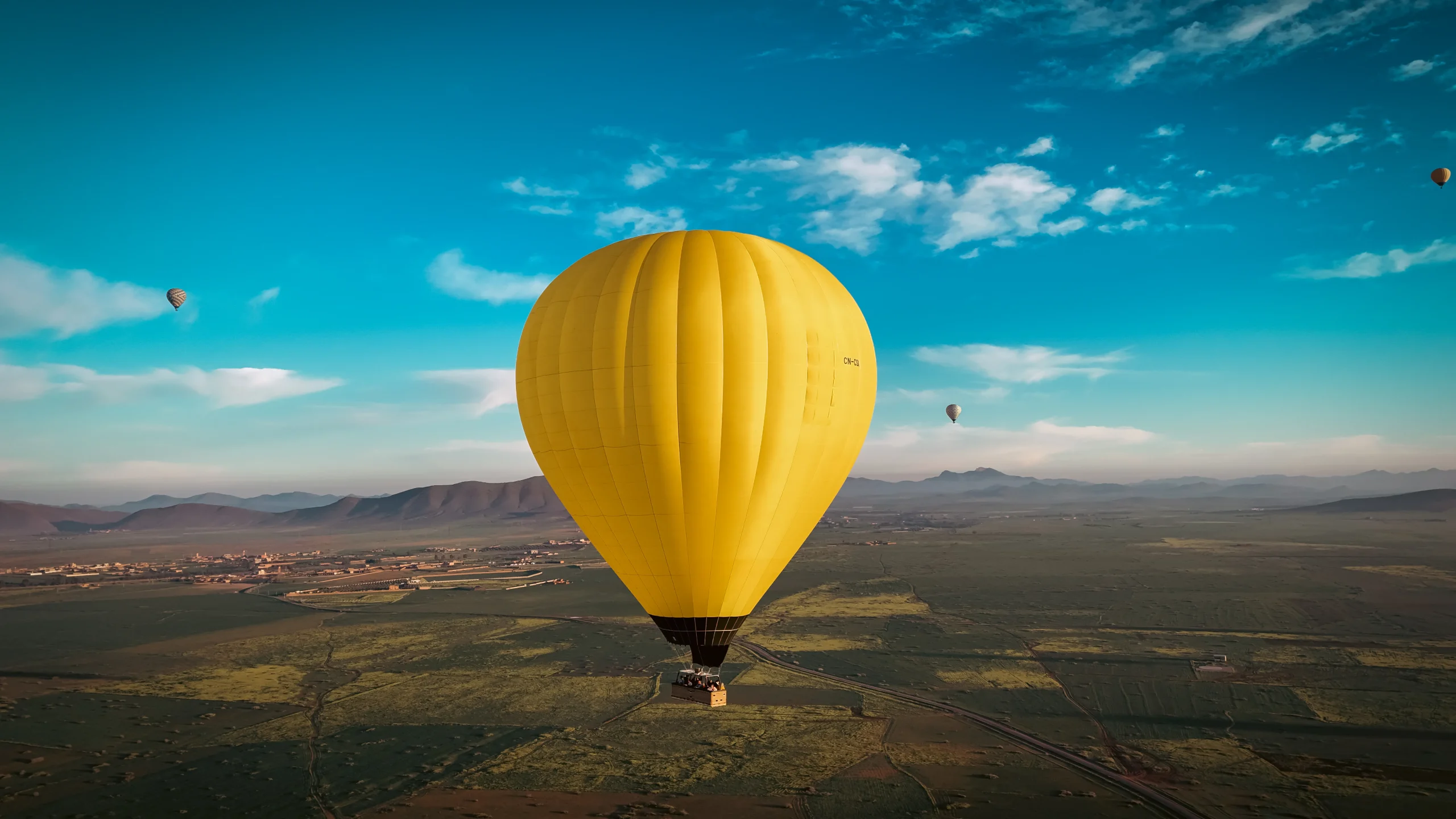 Two hot air balloons silhouetted against golden sunrise sky over Atlas Mountains in Marrakech Morocco