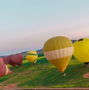 Hot air balloon flight over Marrakech at sunrise with Atlas Mountains in the background
